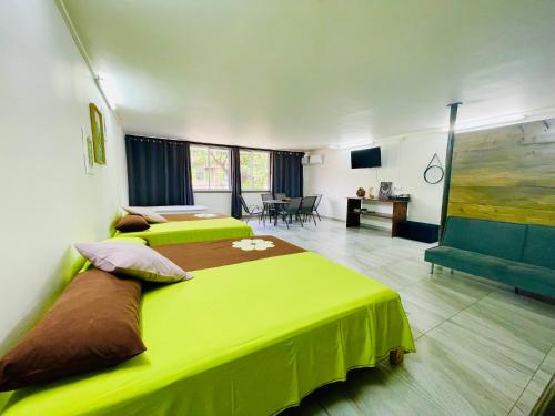2 Betten in einem Zimmer mit einer grünen Decke in der Unterkunft J&D Lodge in Papeete