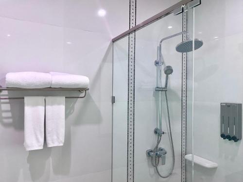 a bathroom with a shower with white towels at Banbua Grand Udon in Udon Thani