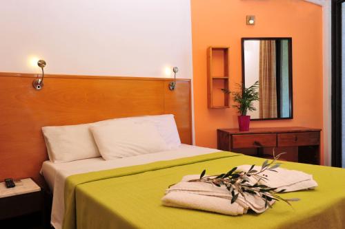 1 dormitorio con 1 cama con manta verde y espejo en Valais Hotel, en Alikanas