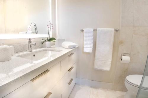 a white bathroom with a sink and a toilet at Villa at St. James Place “H”, Luxury, Pet Friendly in Miami