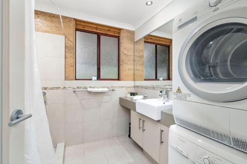 a bathroom with a washing machine and a washer at Goanna Cottage - Woodstone Estate in Dunsborough