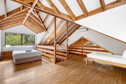 a attic bedroom with two beds and wooden beams at Goanna Cottage - Woodstone Estate in Dunsborough