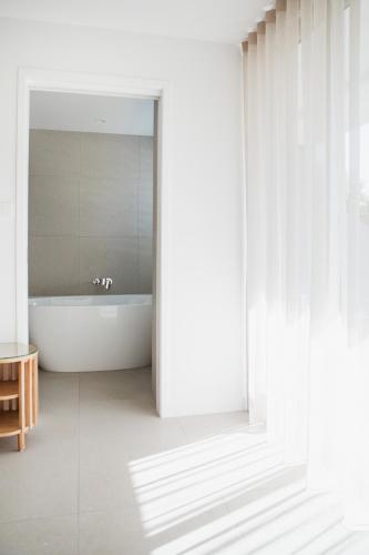 a white bathroom with a tub and a mirror at Netanya Noosa Beachfront Resort in Noosa Heads