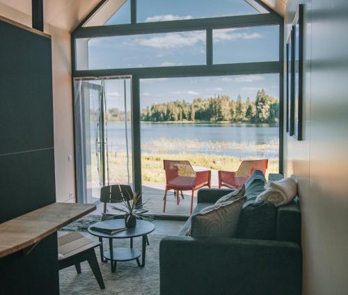 a living room with a couch and a view of a lake at PullanHouse Laima - small and cosy lakeside holiday house in Alūksne