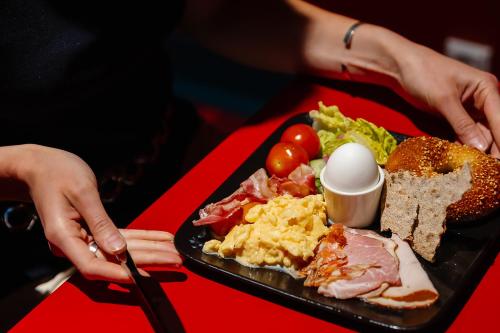 a plate of breakfast food on a red table at Hotel AX in Helsinki