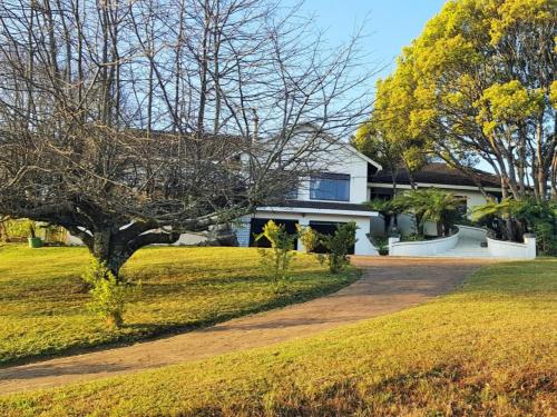 a white house with a tree and a driveway at Paradise View Guesthouse in Graskop
