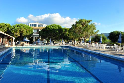 a large blue swimming pool with chairs and trees at Valais Hotel in Alikanas