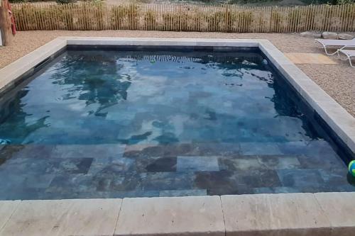 uma piscina com água azul num quintal em Le petit écureuil em Saint-Saturnin-dʼApt