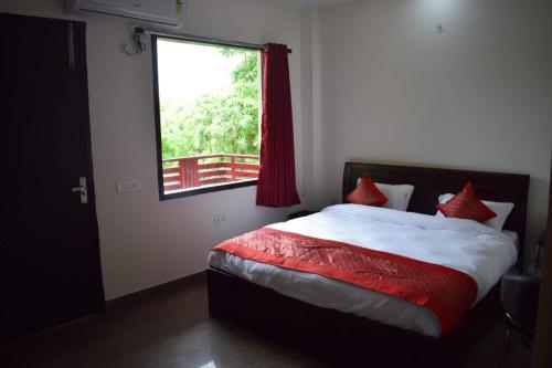 a bedroom with a bed with red pillows and a window at The Starling BnB in Greater Noida