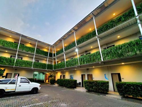 a white truck parked in front of a building with plants at Hotel Sampurna Cirebon in Cirebon