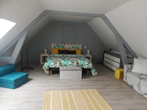 a bedroom with a bed and a couch in a attic at Les Terrasses du Pigeonnier, Duplex 4 pers en Baie de Somme in Vron