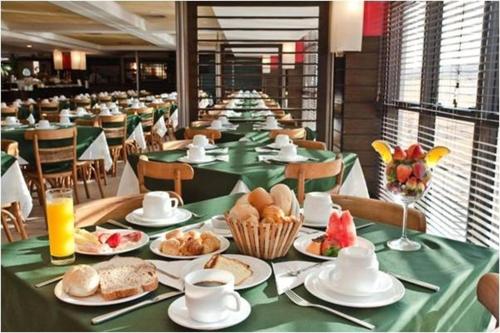 una fila de mesas con platos de comida. en Studio no Jurerê Beach Village - Pé na areia, en Florianópolis