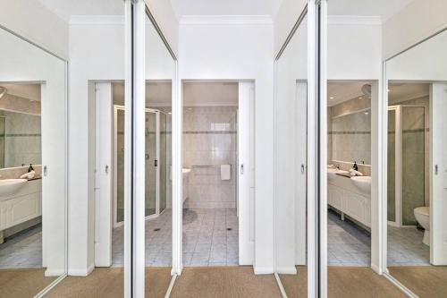 La salle de bains est pourvue de murs blancs et de portes en verre. dans l'établissement Lifestyle Rich Waterfront Residence with Bay Views, à Larrakeyah