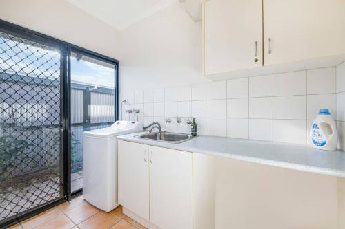 - une cuisine blanche avec un évier et un lave-vaisselle dans l'établissement Lush Home in Trendy Parap with Private Pool, à Paraparap