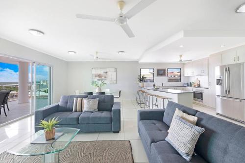 a living room with two blue couches and a kitchen at Alta Vista - City View Oasis in the Heart of Darwin in Darwin