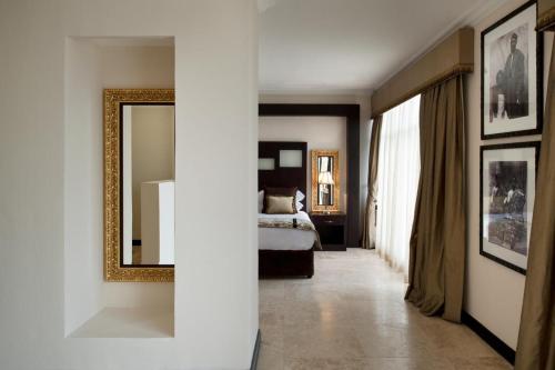 a bedroom with a bed and a mirror on the wall at Villa Monticello Boutique Hotel in Accra