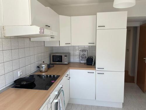 FlyHigh Apartment Stuttgart VS2 في شتوتغارت: مطبخ ابيض مع دواليب بيضاء وموقد