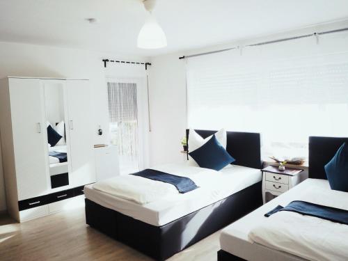 2 Betten in einem Schlafzimmer mit weißen Wänden und blauen Kissen in der Unterkunft Villa Natur Ferienwohnung & Monteurwohnung in Mühlhausen