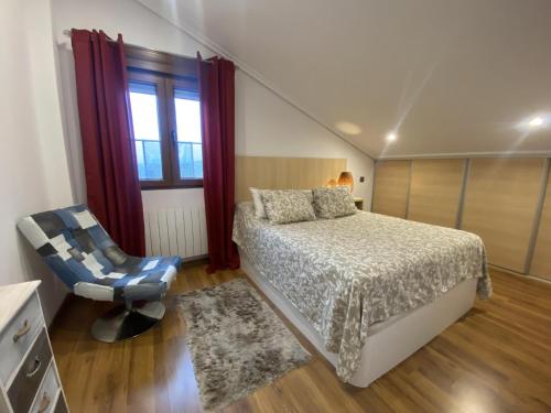 usgo beach apartment في Miengo: غرفة نوم بسرير وكرسي ونافذة