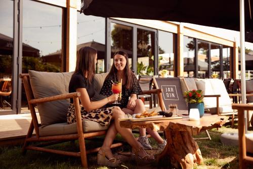 two women sitting on a chair under an umbrella at Van der Valk Hotel Beveren in Beveren