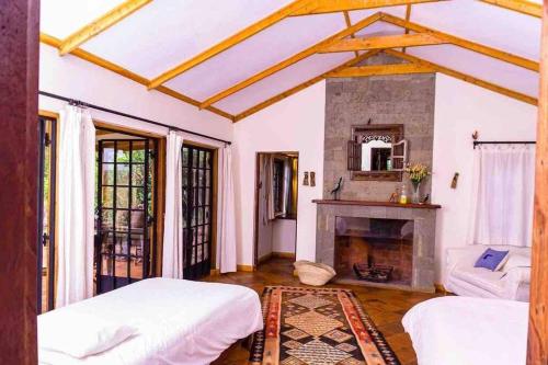 sypialnia z 2 łóżkami i kominkiem w obiekcie Chui Cottage with tennis facing Mt Kenya & near Ngare Ndare w mieście Timau