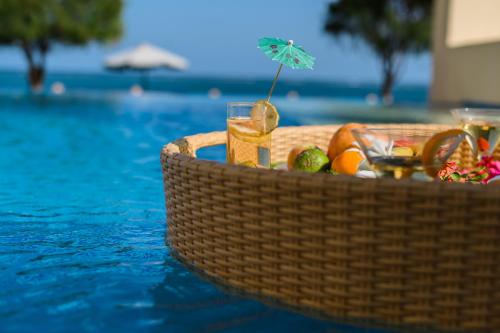 a basket of fruit and a drink in a swimming pool at Cocoa Boutique Hotel in Mombasa