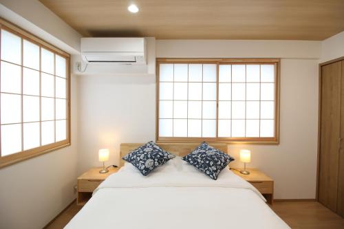 a bedroom with a white bed and two windows at Uhome Suido Apartment SD in Tokyo