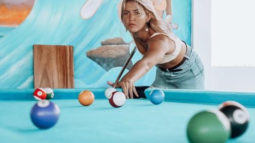 a woman is playing a game of pool at Swell Hotel, Pool Bar & Restaurant in Tanah Lot