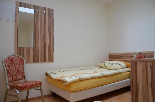 1 dormitorio con cama, silla y espejo en Gościniec Podkowa, en Wlodawa