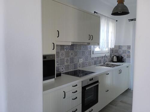 a white kitchen with white cabinets and a sink at Stilvi Milos in Plaka Milou