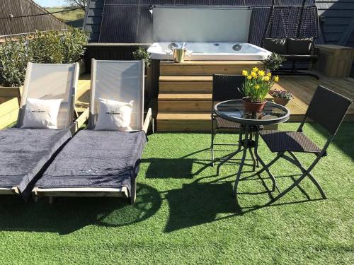 two beds and a table in a yard with a tub at Stunning Luxury Duplex with Hot Tub and AirCon in Glenfarg