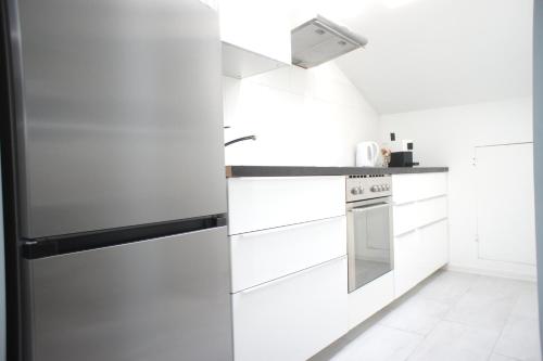 a kitchen with white cabinets and a refrigerator at Hotel Böke Rheinfelden in Rheinfelden