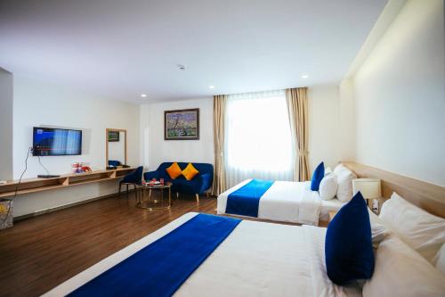 a hotel room with two beds and a television at Sandals Star Hotel in Ðưc Trọng