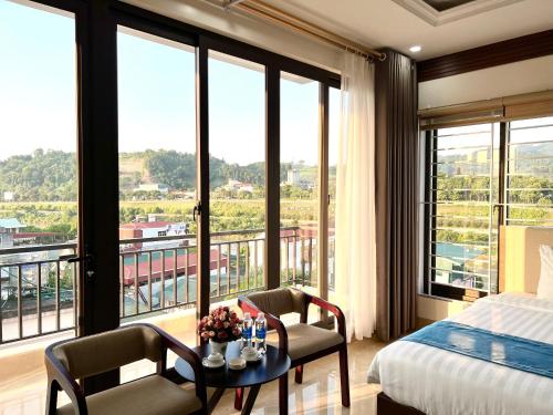 1 dormitorio con 1 cama, mesa, sillas y ventanas en Khách sạn Ngọc Hà en Lao Cai