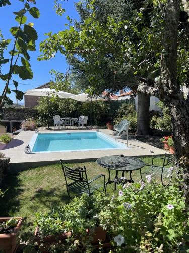 a pool with a table and chairs next to a yard at Casa do Beco B&B Douro - Guest House in Parambos