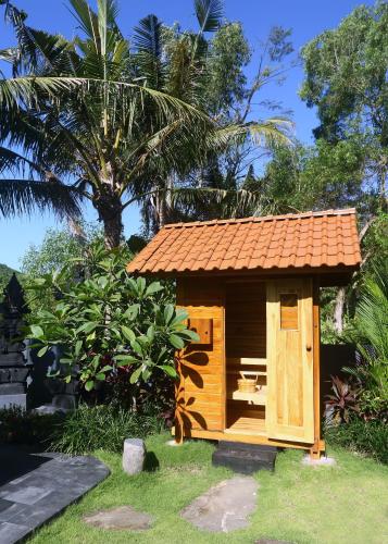a small wooden shed with a bench in the grass at The Hidden Escapes Manggis- Stunning Hidden Gem Villa with Pool, Sauna & Ice Bath in Padangbai