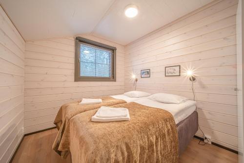 two beds in a small room with wooden walls at Levillas Sointuilevi 1A72, 2 ski pass included in Levi