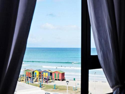 a view of a beach with colorful houses and the ocean at African Soul Surfer in Muizenberg