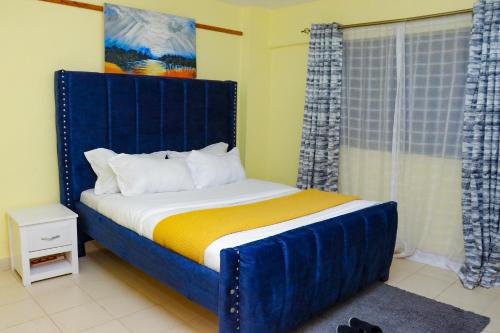 a bed with a blue headboard in a room at Lovely One bedroom Apartment , TRM Drive Nairobi in Nairobi