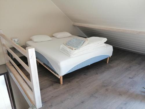 ein kleines Bett mit weißer Bettwäsche und Kissen in einem Zimmer in der Unterkunft Gîte Ferme d'hurtaux in Froidchapelle