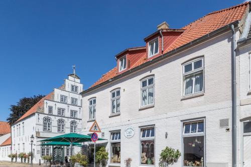 a row of white buildings with a clock tower at Blumenhaus-apartment Friedrichstadt in Friedrichstadt