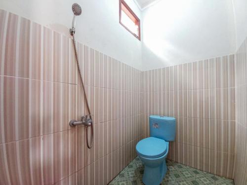 a bathroom with a blue toilet and a shower at Villa Kampoeng City Pacet Mitra RedDoorz in Mojokerto