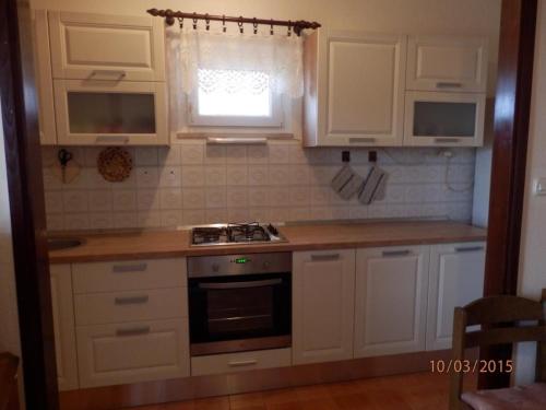 a kitchen with white cabinets and a stove and a window at Apartments Vesna & Ivica in Mirce