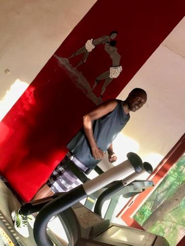 a man standing next to a treadmill in a gym at Maison Couleur Passion in Nianing