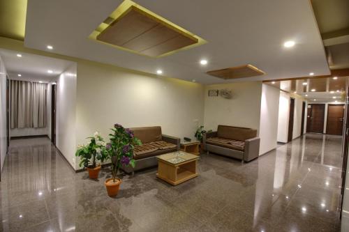 a lobby with couches and plants in a building at Hotel The Furat Inn in Vapi