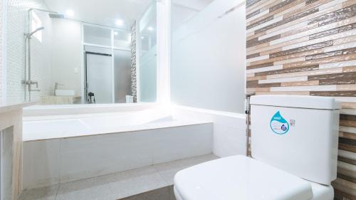 a bathroom with a white toilet and a bath tub at RedDoorz at DBuilders Rooms Lower Bicutan in Manila