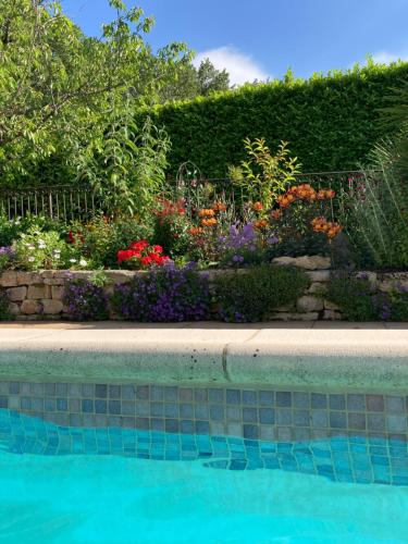a garden with colorful flowers and a swimming pool at Les Hauts d'Eyragues gite Rêverie Meublé classé 4 étoiles in Eyragues