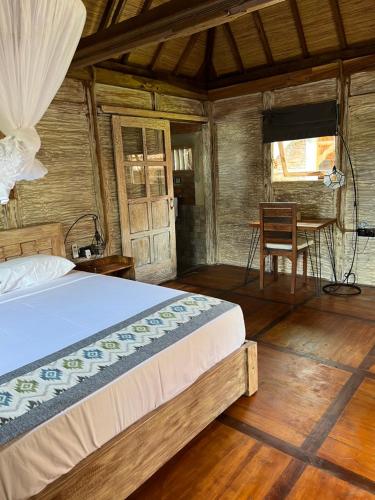 a bedroom with a bed and a table and a chair at PINOKKIO B&B Restaurant in Jimbaran