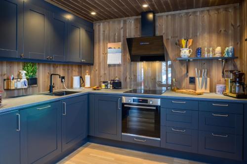eine Küche mit blauen Schränken und einem Herd in der Unterkunft Superior Cabin Ballstad Lofoten in Ballstad