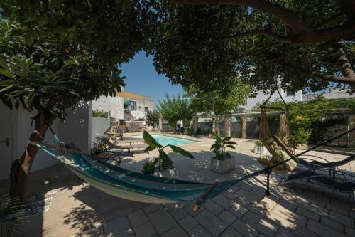 a hammock hanging from a tree next to a pool at B&B Palazzo la Traja in Gagliano del Capo